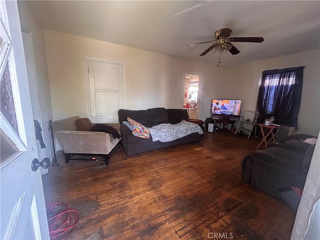 living room with dark wood-type flooring and ceiling fan