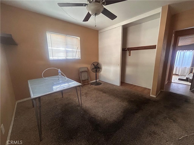 interior space with ceiling fan and dark colored carpet