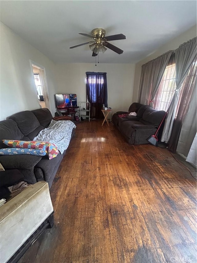 living room with dark wood-type flooring and ceiling fan