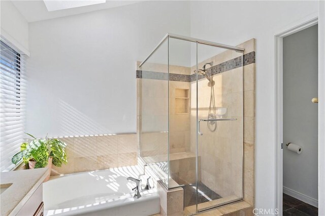 bathroom with tile patterned floors, vanity, a skylight, and separate shower and tub