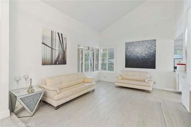 living room with light wood-type flooring and high vaulted ceiling