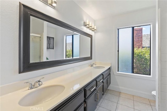 bathroom featuring vanity, toilet, a healthy amount of sunlight, and tile patterned flooring