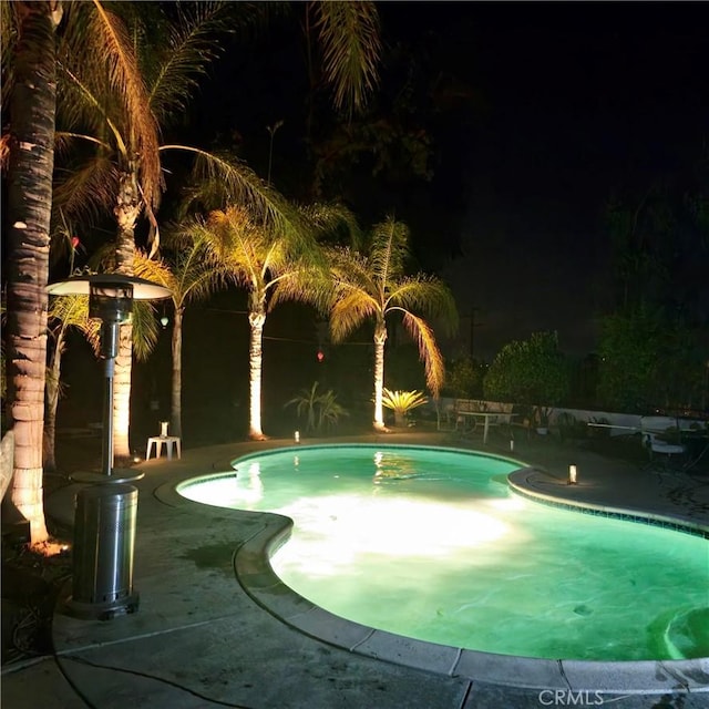 pool at twilight featuring an outdoor pool and a patio