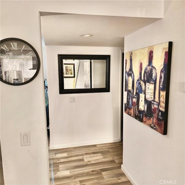 hallway featuring wood finished floors and baseboards