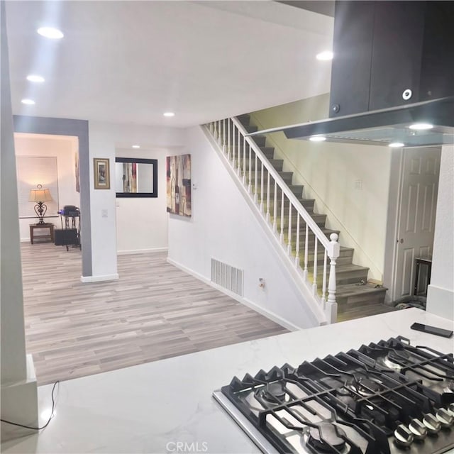 staircase with baseboards, visible vents, wood finished floors, and recessed lighting