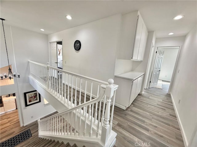 hall featuring baseboards, recessed lighting, an upstairs landing, and light wood-style floors