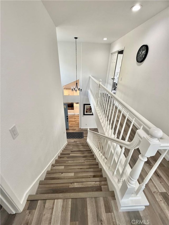 stairway with a chandelier, recessed lighting, baseboards, and wood finished floors