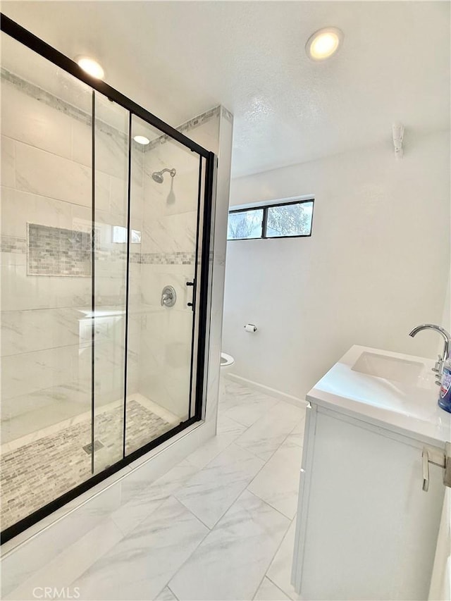 bathroom with marble finish floor, toilet, vanity, and a shower stall