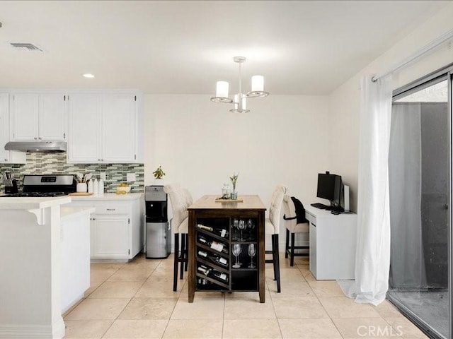 kitchen featuring hanging light fixtures, backsplash, white cabinets, light tile patterned floors, and stainless steel range with electric cooktop