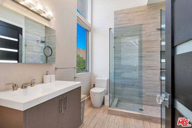 bathroom with toilet, a shower with shower door, and vanity