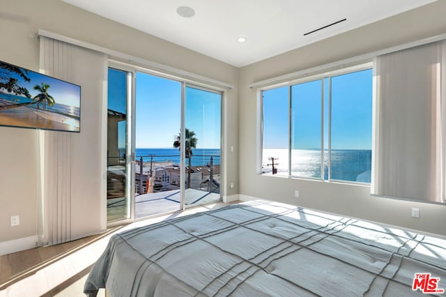 bedroom featuring light hardwood / wood-style floors, access to outside, and a water view