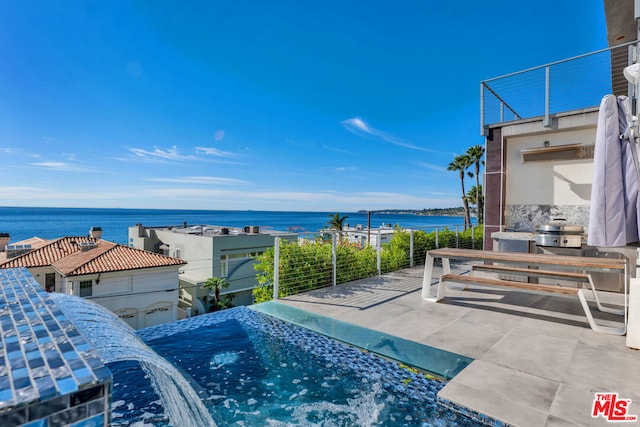 view of swimming pool featuring a patio area, exterior kitchen, and a water view