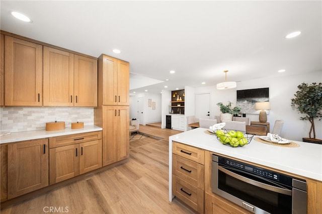 kitchen with light wood-type flooring, hanging light fixtures, and tasteful backsplash