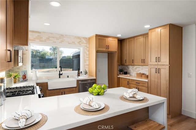 kitchen featuring wood-type flooring, dishwasher, sink, kitchen peninsula, and backsplash