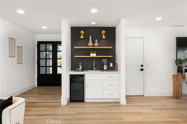 bar with sink, white cabinetry, beverage cooler, and light hardwood / wood-style flooring