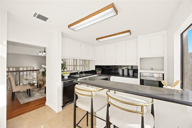 kitchen featuring white cabinets, black dishwasher, a wealth of natural light, and oven