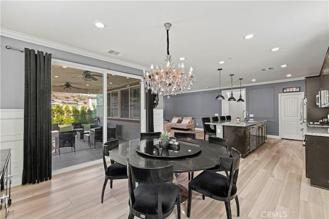 dining area with ceiling fan, sink, light hardwood / wood-style flooring, and crown molding