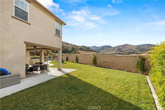 view of yard featuring a mountain view, ceiling fan, and a patio