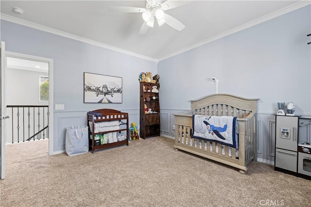 bedroom with ceiling fan, carpet, ornamental molding, and a crib