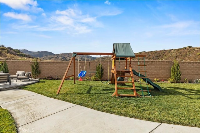 view of jungle gym with a mountain view, a patio area, and a lawn