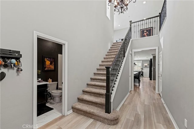 stairway featuring hardwood / wood-style floors, an inviting chandelier, and a towering ceiling