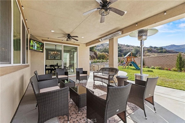 view of patio / terrace featuring a mountain view, ceiling fan, a playground, and an outdoor hangout area