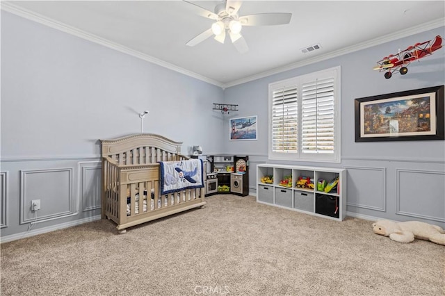 bedroom featuring ceiling fan, carpet, crown molding, and a crib