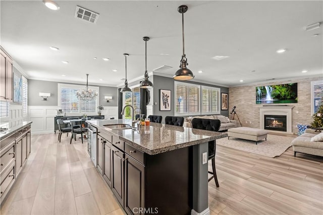 kitchen with crown molding, dark brown cabinets, sink, decorative light fixtures, and a breakfast bar