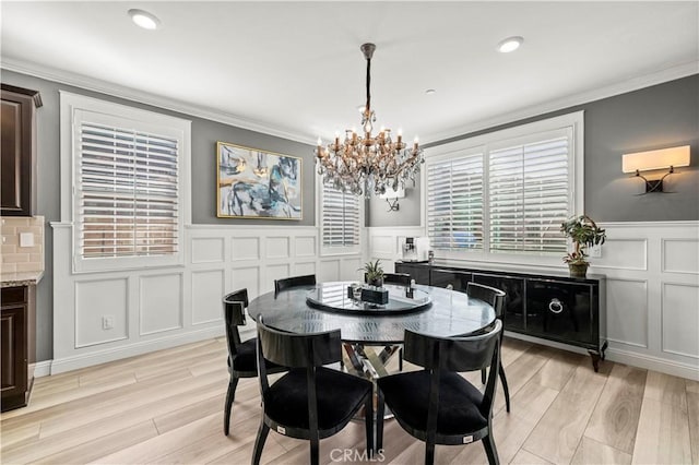 dining space featuring crown molding, light wood-type flooring, and a notable chandelier