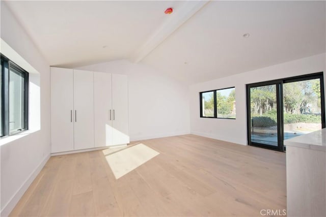 interior space with a healthy amount of sunlight, lofted ceiling with beams, and light wood-type flooring