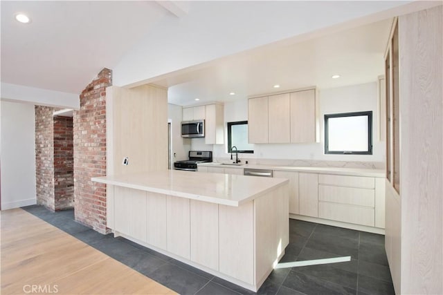 kitchen featuring a healthy amount of sunlight, appliances with stainless steel finishes, vaulted ceiling, and a kitchen island