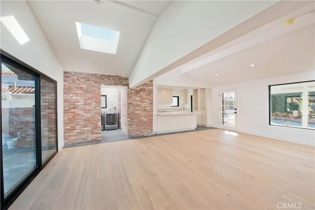 unfurnished living room with vaulted ceiling with skylight and light hardwood / wood-style floors