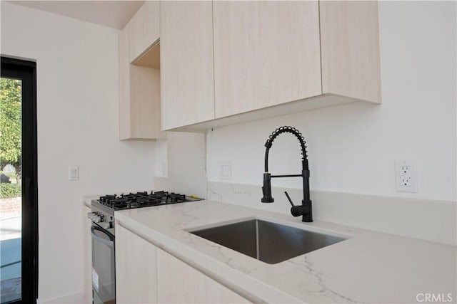 kitchen featuring sink, gas range, and light brown cabinets