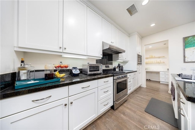 kitchen featuring light hardwood / wood-style floors, white cabinets, stainless steel appliances, and dark stone counters