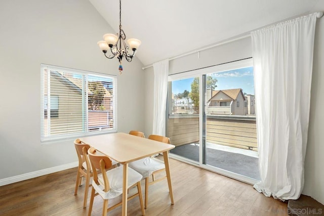 dining area with lofted ceiling, hardwood / wood-style floors, and a chandelier