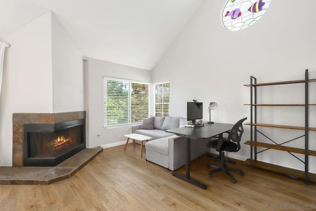 office space with high vaulted ceiling, a fireplace, and hardwood / wood-style floors