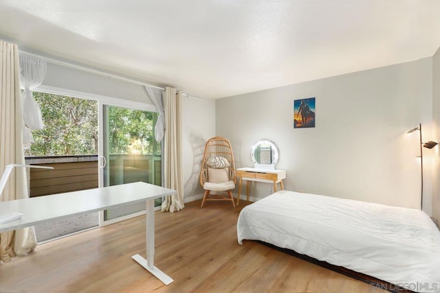 bedroom with hardwood / wood-style floors and access to exterior