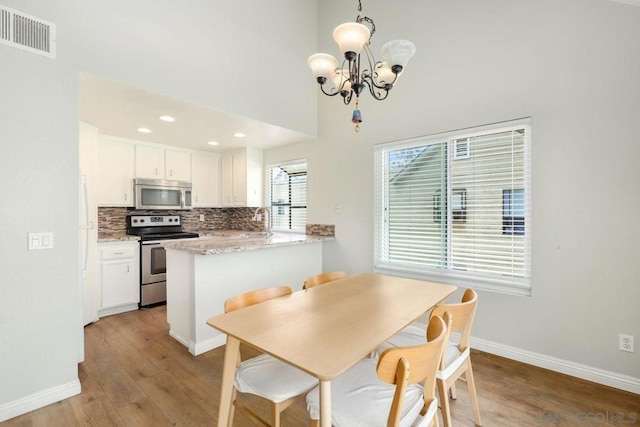 dining space with an inviting chandelier, sink, a high ceiling, and light wood-type flooring