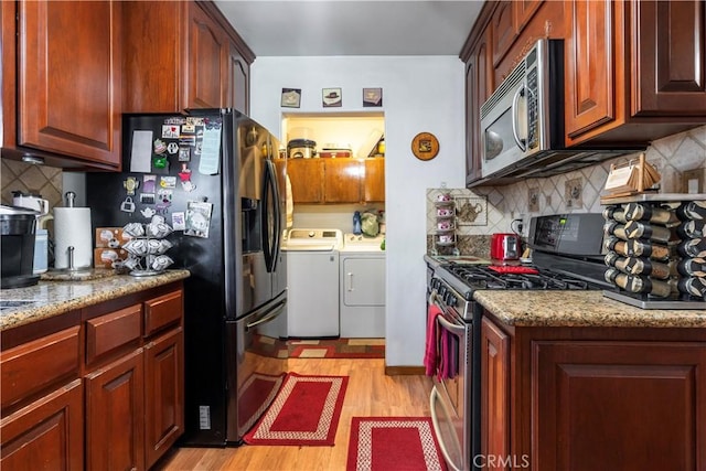 kitchen featuring light stone counters, independent washer and dryer, stainless steel appliances, and light hardwood / wood-style flooring