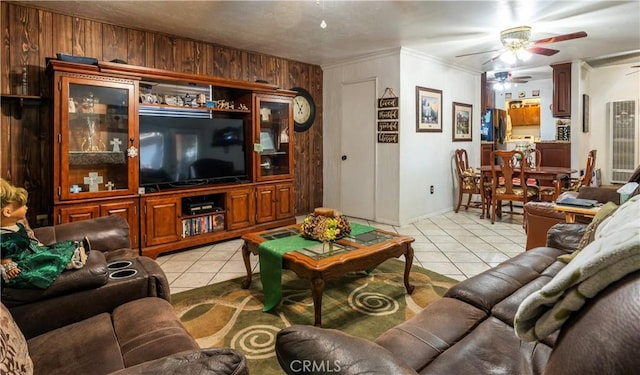 tiled living room featuring ceiling fan, ornamental molding, and wooden walls