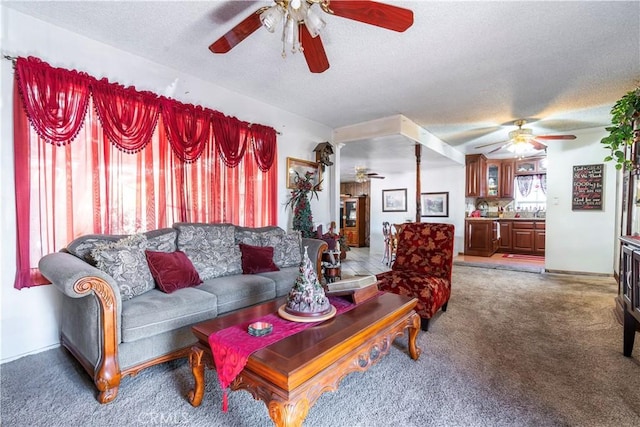 living room with dark colored carpet, ceiling fan, and a textured ceiling