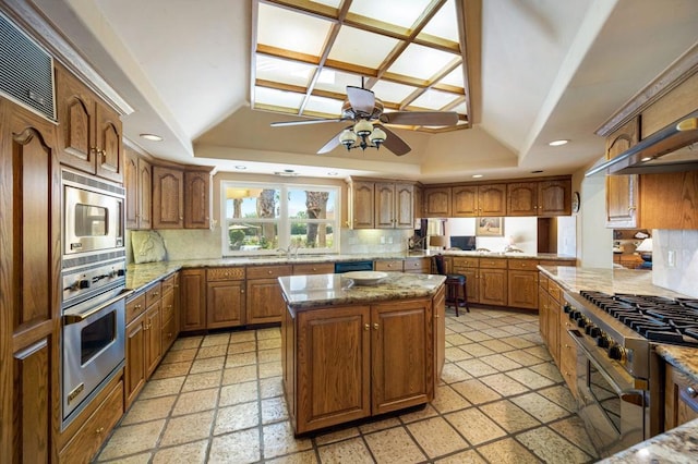 kitchen featuring a kitchen island, tasteful backsplash, a tray ceiling, and appliances with stainless steel finishes