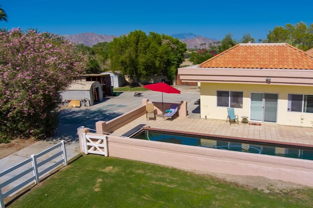 back of property featuring a lawn, a mountain view, and a patio area