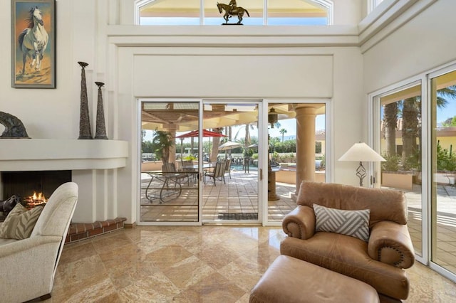 doorway with a brick fireplace, a high ceiling, and a wealth of natural light