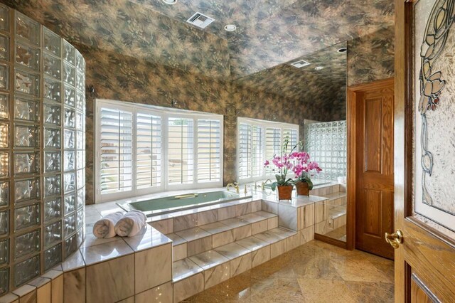 bathroom with vaulted ceiling and tiled bath