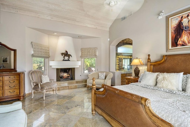 bedroom with a large fireplace and high vaulted ceiling