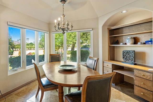 dining area with an inviting chandelier, lofted ceiling, and built in desk