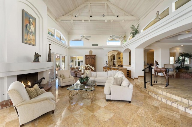 living room featuring ceiling fan, high vaulted ceiling, beamed ceiling, and plenty of natural light