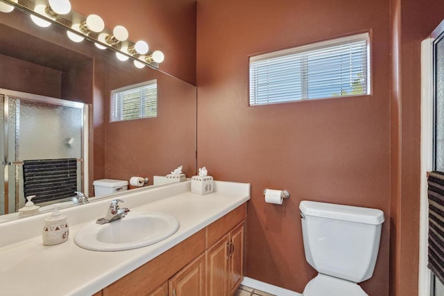 bathroom featuring a shower with shower door, plenty of natural light, toilet, and vanity