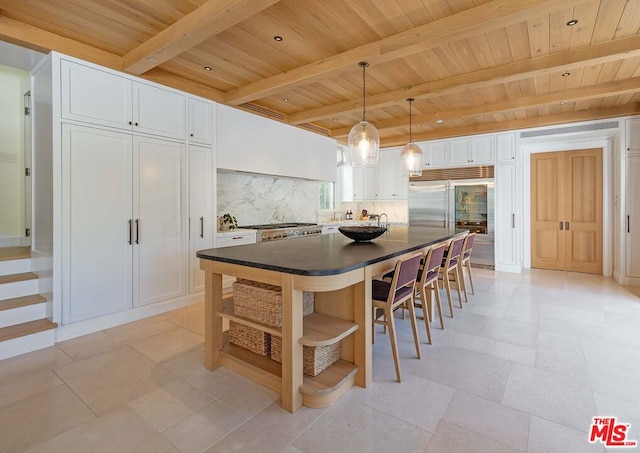 kitchen featuring white cabinets, a center island, decorative light fixtures, decorative backsplash, and beam ceiling